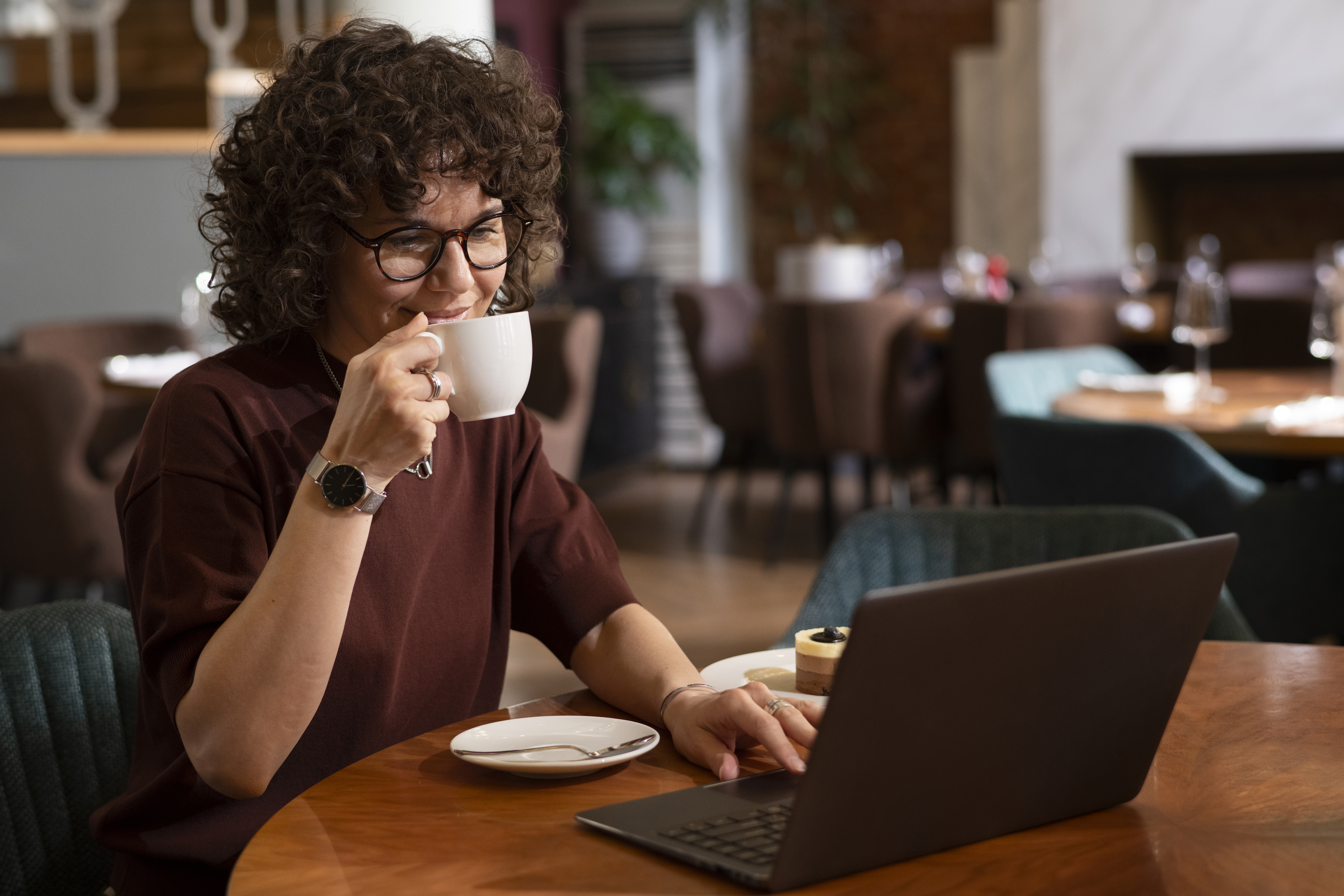 Pessoa trabalhando com um notebook em uma cafeteria aconchegante